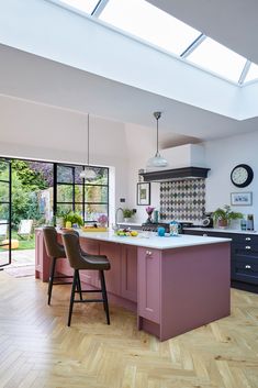 a woman is standing in the middle of a kitchen with purple cabinets and an island