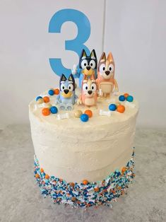 a birthday cake with three cartoon characters on it and the number 3 in the background