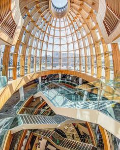 the inside of a large building with many windows and wooden ceilinging, looking down at an escalator