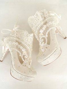 two white high heeled shoes with lace and bows on the heels are shown in front of a white background