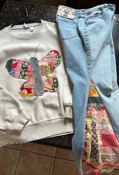 two pieces of clothing sitting on top of a counter next to each other, one with a butterfly applique on it