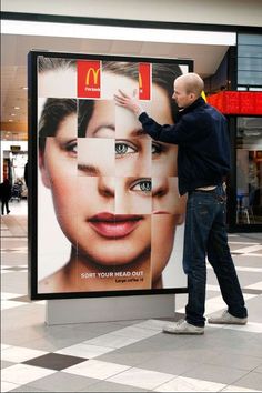 a man standing next to a giant advertisement for mcdonald's