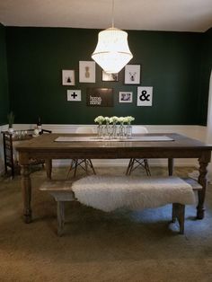 a dining room table and bench with pictures on the wall