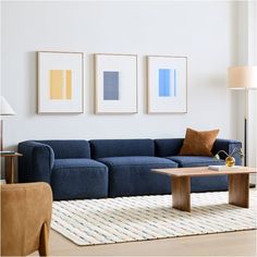 a living room with blue couches and pictures on the wall above it, along with a coffee table