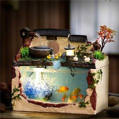 an aquarium with fish and plants in it is displayed on a wooden table next to other items