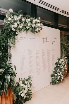 a large white sign with greenery and flowers on it