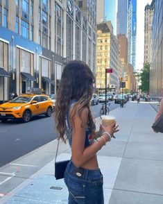 a woman standing on the sidewalk holding a cup of coffee