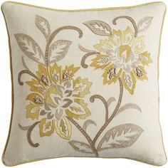 a white and yellow pillow with flowers on the front, gold trim around the edges