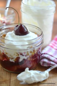 two jars filled with dessert sitting on top of a wooden table