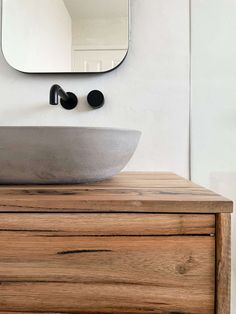 a bathroom sink sitting on top of a wooden counter next to a mirror and cabinet