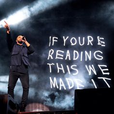 a man standing on top of a stage with his hand up in the air while holding a microphone