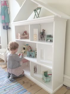 a small child is playing with toys in a white bookcase