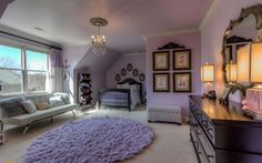 a baby's room with purple walls and carpeted flooring, chandelier, crib, dressers, and large windows