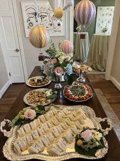 a table filled with lots of food on top of a wooden table next to balloons