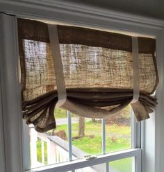 an open window with curtains hanging from it's side and the blinds pulled back