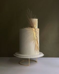 there is a white cake with gold decoration on the top and bottom, sitting on a stand