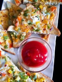 several pieces of bread with different toppings and a small bowl of ketchup