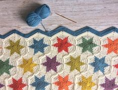 a crocheted blanket with multicolored stars on it next to knitting needles