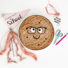 a chocolate chip cookie with eyeballs on it next to scissors and other crafting supplies