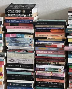 a stack of books sitting on top of a wooden shelf next to a white wall