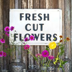 fresh cut flowers are displayed in vases next to a sign that says fresh cut flowers