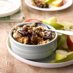 a bowl filled with cereal sitting on top of a table next to an apple slice