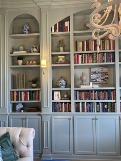 a living room filled with lots of bookshelves covered in bookcases and a chandelier