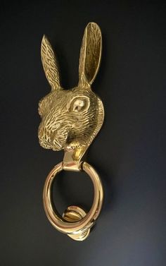 a golden metal key chain with a rabbit's head hanging from the front, on a black background