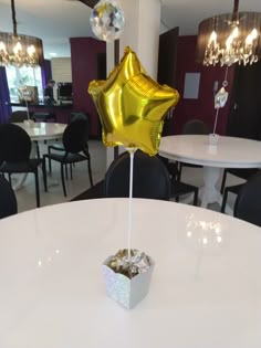 a gold star balloon sitting on top of a table in a room filled with black chairs