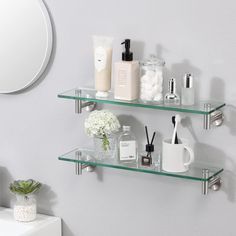 two glass shelves with soap, lotion and other items on them in a bathroom