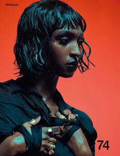 a woman with black makeup and jewelry on her face is standing in front of a red background