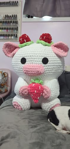 a crocheted stuffed animal sitting on top of a bed next to a dog