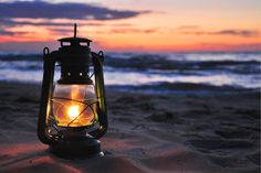 a lantern sitting on top of a sandy beach