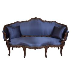 an antique couch with blue upholstered cushions