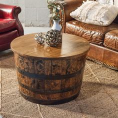 a wooden barrel coffee table sitting on top of a rug next to a leather couch