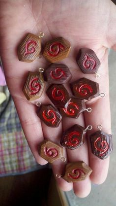 a person's hand holding several small chocolates with letters on them and charms attached to them