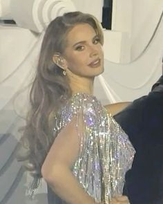 a man and woman standing next to each other in front of a white curtain with silver sequins on it