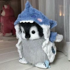 a stuffed animal that is wearing a blue and white shark costume on it's head