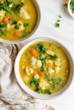 two white bowls filled with soup on top of a table