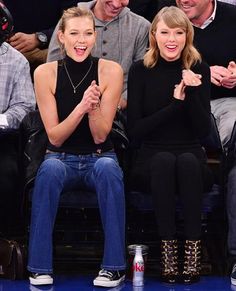 two women sitting next to each other in front of a crowd at a basketball game