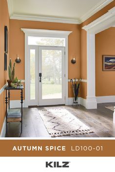 a living room with an orange wall and white trim on the door, along with a rug that says kiltz