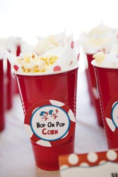 red cups filled with popcorn sitting on top of a table next to cupcakes