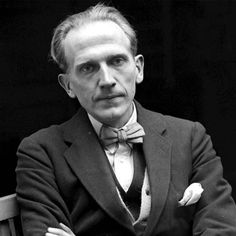 a man in a suit and bow tie sitting on a bench with his arms crossed