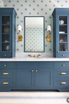 a bathroom with blue cabinets and gold accents