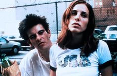 a man and woman standing next to each other in front of a chain link fence