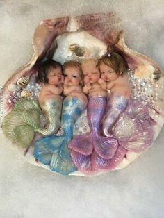 four babies are laying in a shell with mermaid tails on their backs and under the shells