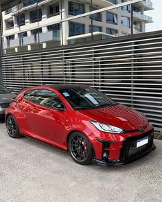 two cars parked next to each other in front of a building with metal slats