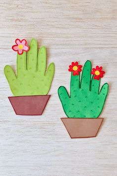 two paper cactus plants sitting on top of a wooden table