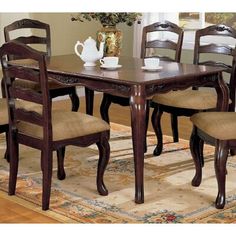 a dining room table with chairs and a vase filled with flowers on top of it