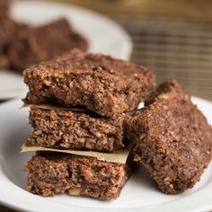 some brownies are stacked on top of each other in front of another plate with one piece cut out